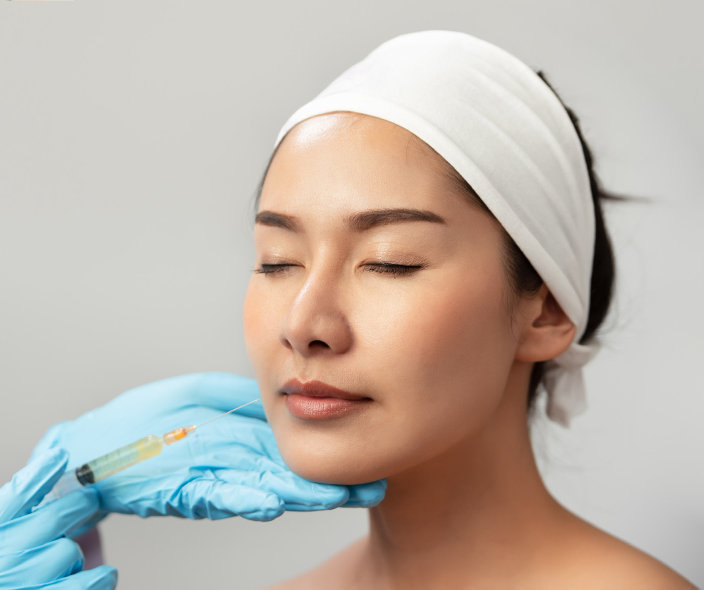 Extreme closeup indoor shot showing lip filler procedure at SPA and wellness salon. A licensed healthcare professional performing dermal filler on her asian female patient.