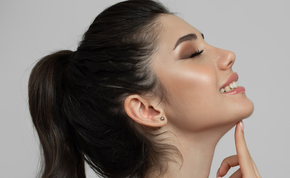 Woman face with smile and lifting effect. Touching chin area with index finger.