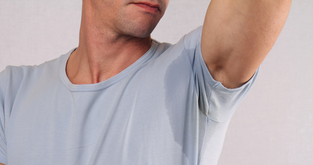 man with excessive sweating under his arms through his shirt
