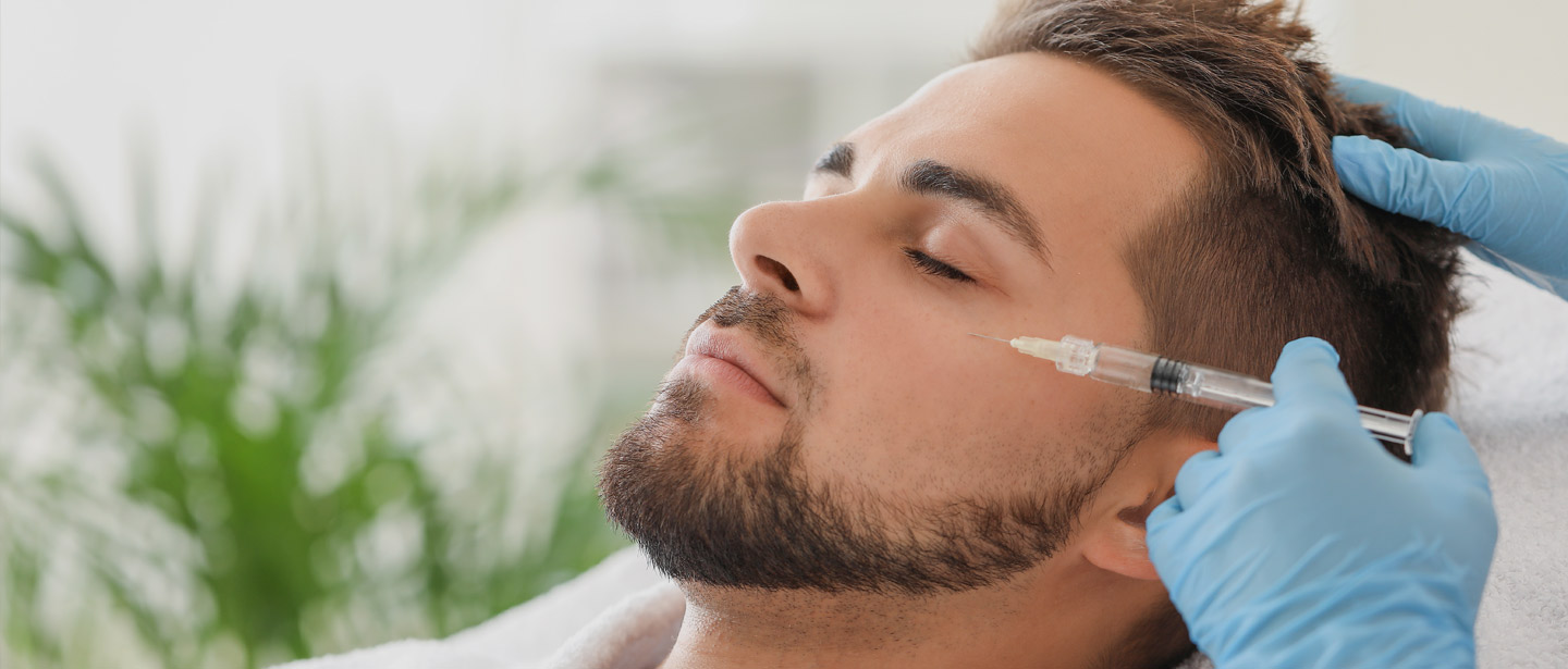 Handsome man receiving filler injection in beauty salon