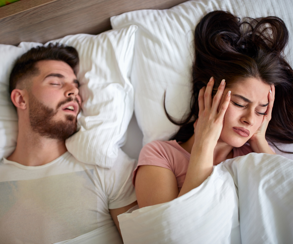 Women in bed with snoring husband