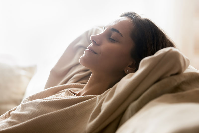 Happy young woman relaxing on comfortable sofa